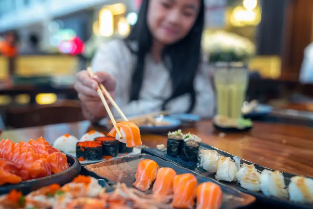 Woman Eating sushi at a restaurant with chopsticks